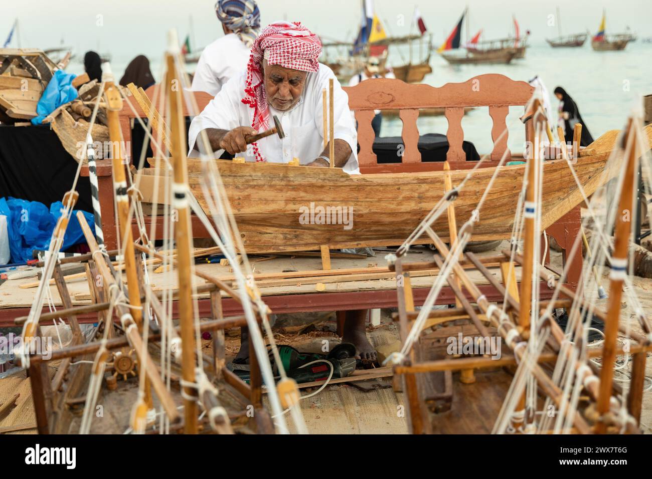 Un artista creativo che costruisce un piccolo modello di una tradizionale barca da pesca araba. Foto Stock