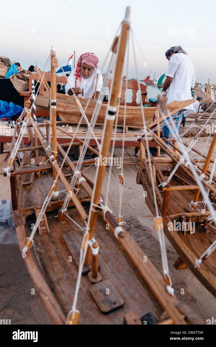 Un artista creativo che costruisce un piccolo modello di una tradizionale barca da pesca araba. Foto Stock