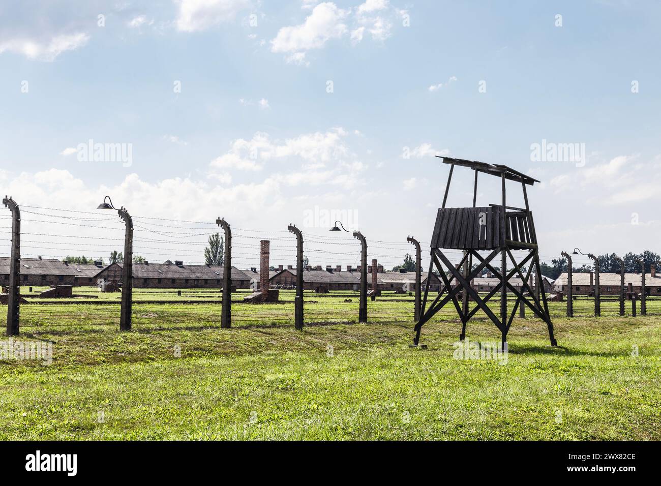 Recinzioni in filo metallico, torre di guardia e caserme dei prigionieri nel campo di concentramento nazista di Auschwitz-Birkenau, Polonia Foto Stock