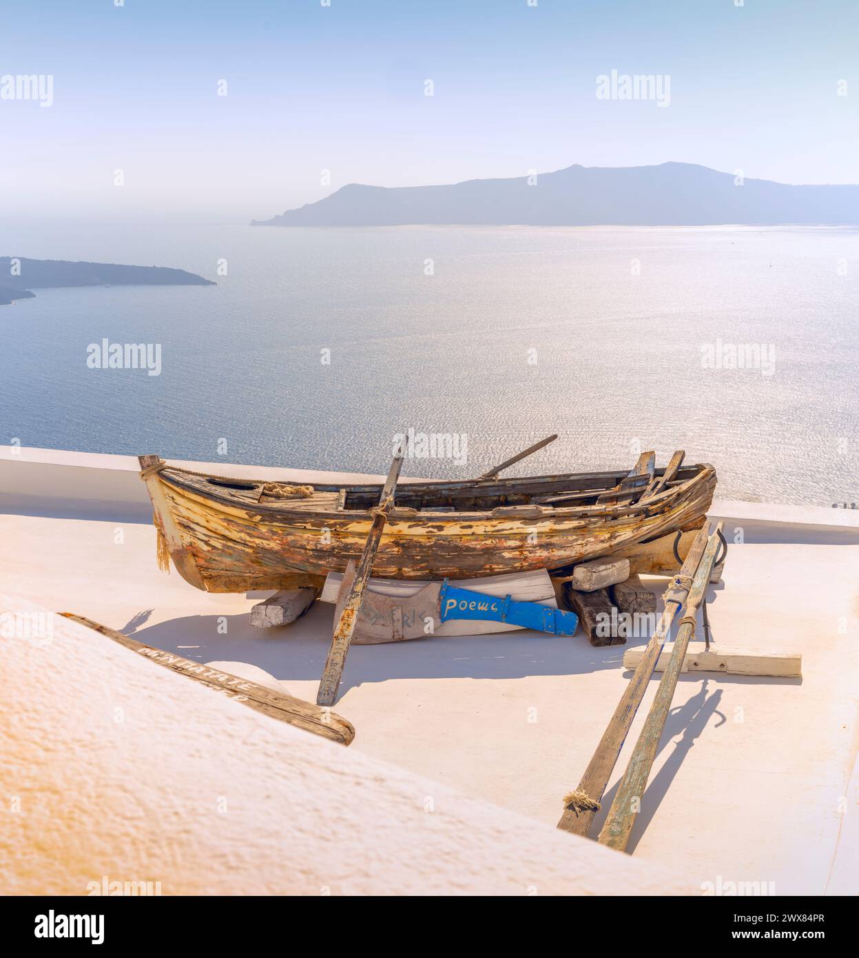La vecchia barca a remi malandata è usata per decorare l'area di fronte a una dimora che si affaccia sulla Caldera di Santorini e sul Mar Egeo Foto Stock