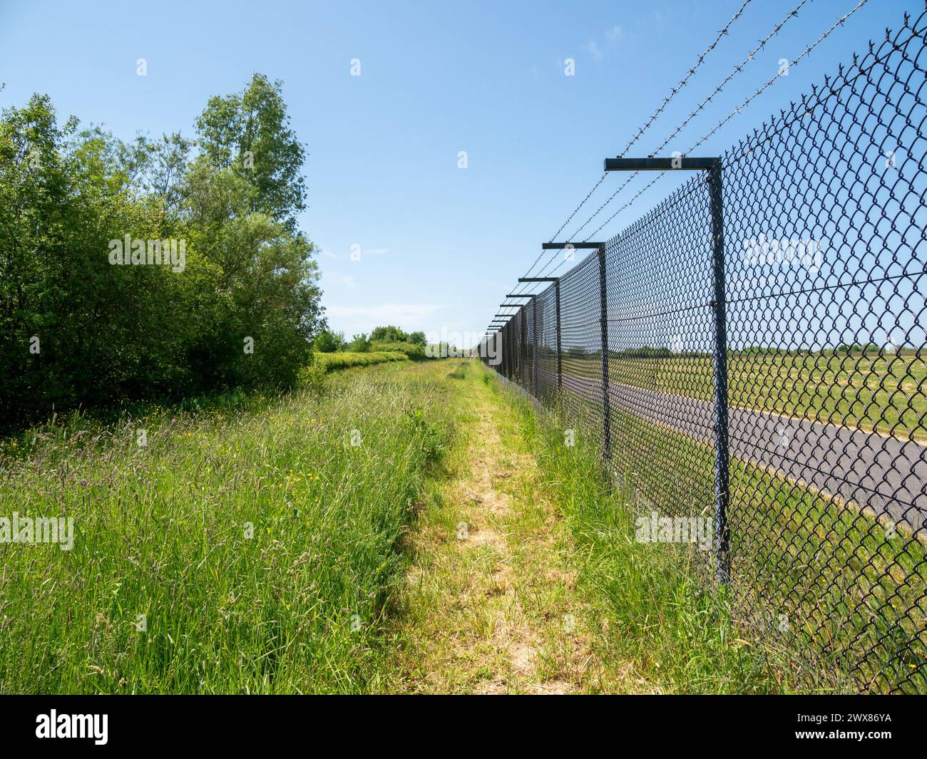 Recinzione perimetrale intorno all'aeroporto internazionale di Manchester, soleggiata giornata estiva con erba verde e cielo azzurro senza nuvole. Foto Stock