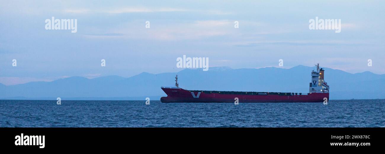Salonicco, Grecia - 3 maggio 2019: Nave da carico nel Golfo delle Terme, ancorata di fronte alle montagne innevate al tramonto. Foto Stock