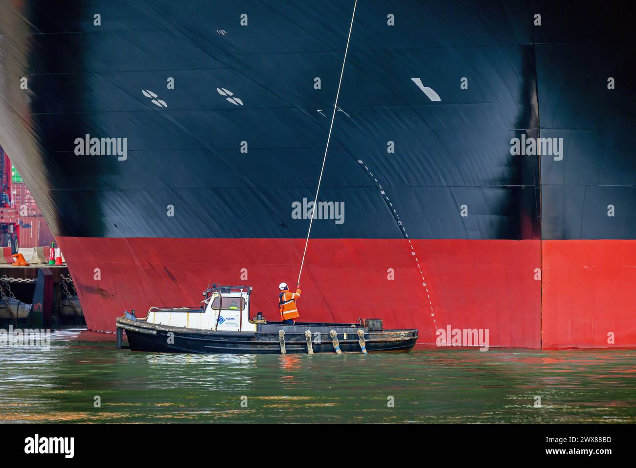 Una nave portuale prende le linee da una nave portacontainer mentre ormeggia al porto di Southampton. Foto Stock