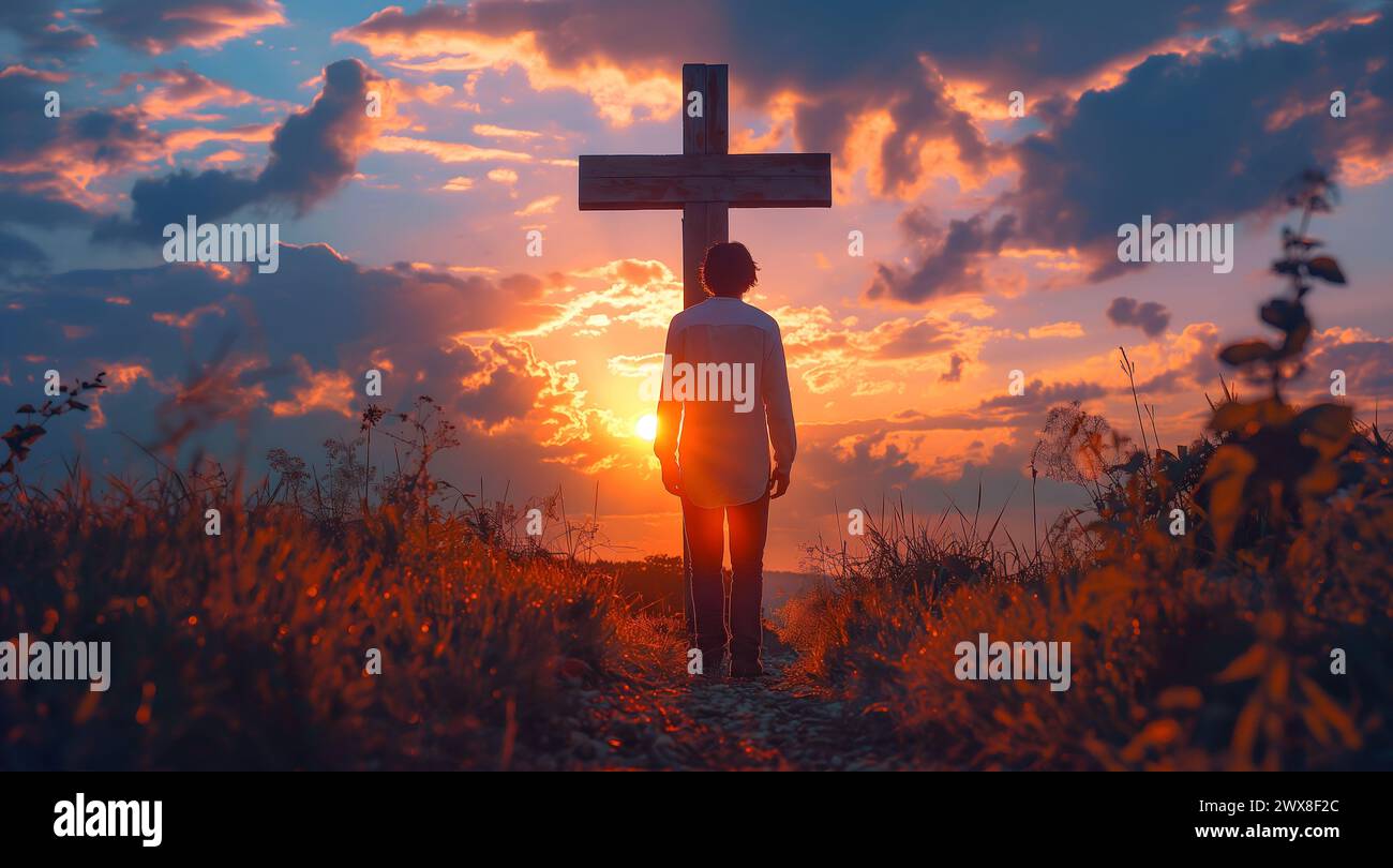 Uomo di fronte alla vecchia croce di legno al tramonto. Cristianesimo e concetto di culto. Foto Stock