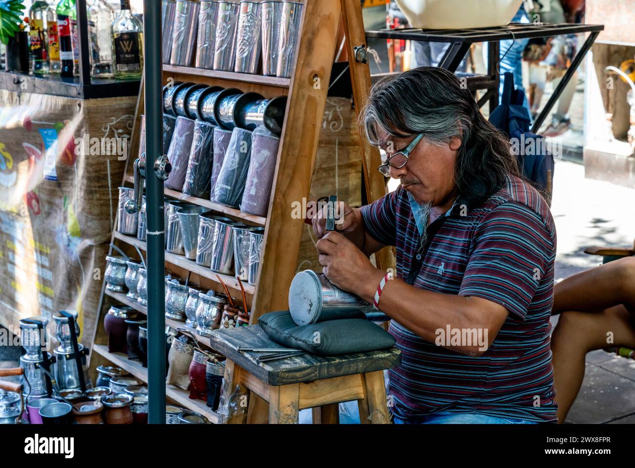 Un uomo incide Una coppa fuori Da Un negozio nel quartiere di la Boca, Buenos Aires, Argentina. Foto Stock