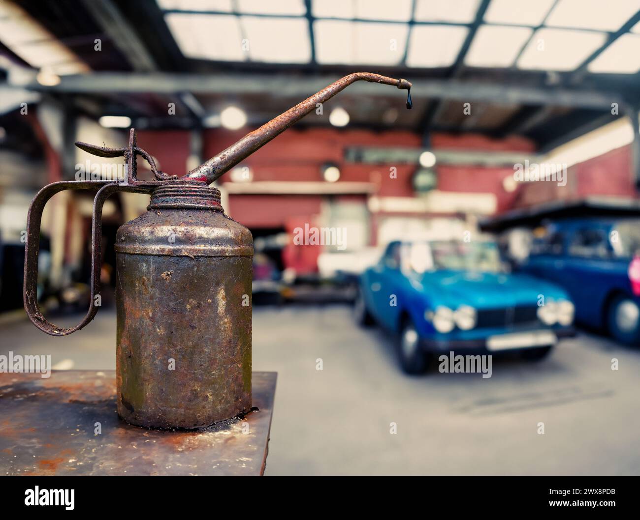 Grungy Rusty lattina con Un gocciolamento d'olio in un negozio di riparazione di automobili con auto d'epoca e spazio copie Foto Stock