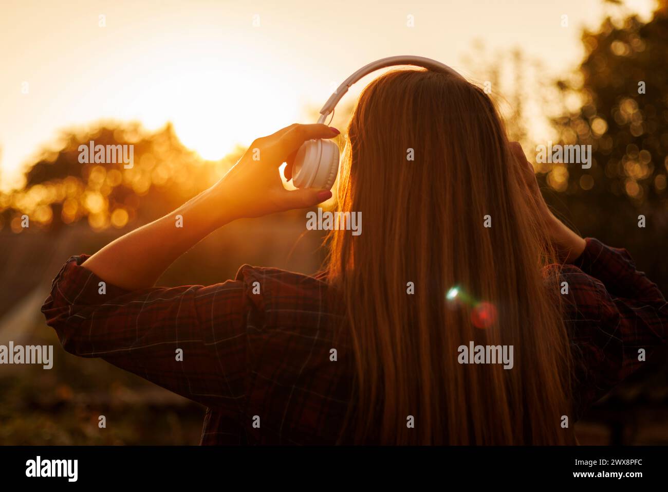 Donna con le cuffie che si gode il tramonto. Foto Stock