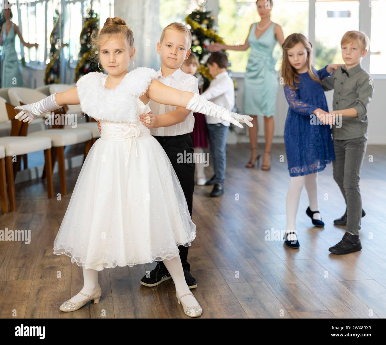 Bambini preadolescenti in abiti eleganti che praticano la danza di coppia nello studio natalizio Foto Stock