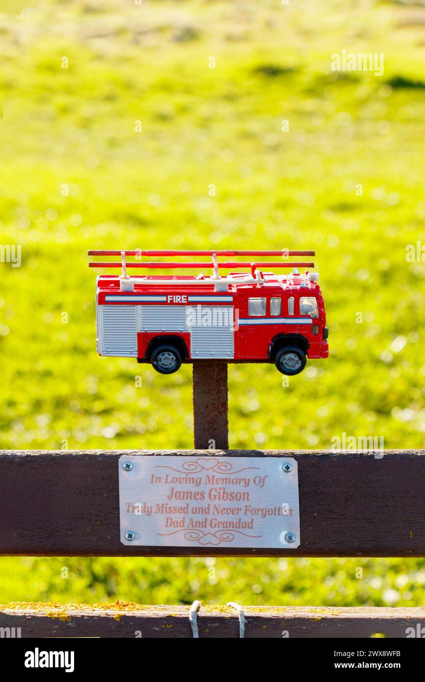Modellino in scala pressofuso di camion dei pompieri montato sulla panchina del parco in memoria di papà e nonno, Blyth Northumberland Foto Stock