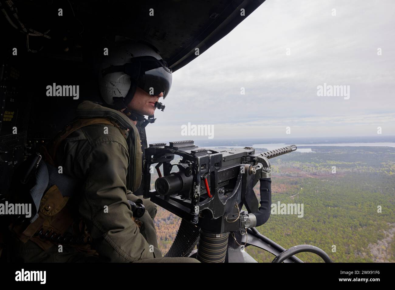 Corbin Sullivan, nativo della Georgia e capo dell'equipaggio UH-1Y Venom con Marine Light Attack Helicopter Squadron (HMLA) 167, guarda fuori da un UH-1Y Venom durante un volo sulla Marine Corps Air Station New River, Carolina del Nord, 26 marzo 2024. L'HMLA-167 ha condotto la consegna di munizioni con guida di precisione per familiarizzare i piloti designati e il personale di ordigno con le procedure appropriate per sparare e maneggiare più tipi di ordigni. L'addestramento al fuoco vivo ha permesso all'HMLA-167 di migliorare l'integrazione con la forza congiunta mentre si addestrava nelle operazioni di aviazione nella guerra marittima-superficie Foto Stock