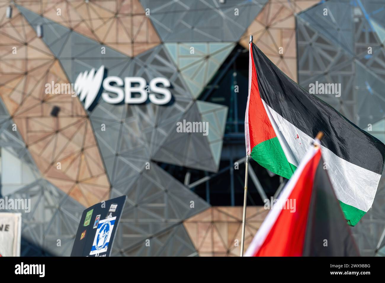 Melbourne, Australia. 28 marzo 2024. Un manifestante inonda una bandiera palestinese in Federation Square vicino all'edificio della TV SBS durante una protesta improvvisa e siediti. A Melbourne si è svolta una protesta pacifica che chiede la fine del conflitto israelo-palestinese. Nonostante una grande risposta della polizia, l'evento rimase nonviolento. Si è verificato un solo arresto, che ha coinvolto un individuo che tentava di interrompere il procedimento. (Foto di Michael Currie/SOPA Images/Sipa USA) credito: SIPA USA/Alamy Live News Foto Stock