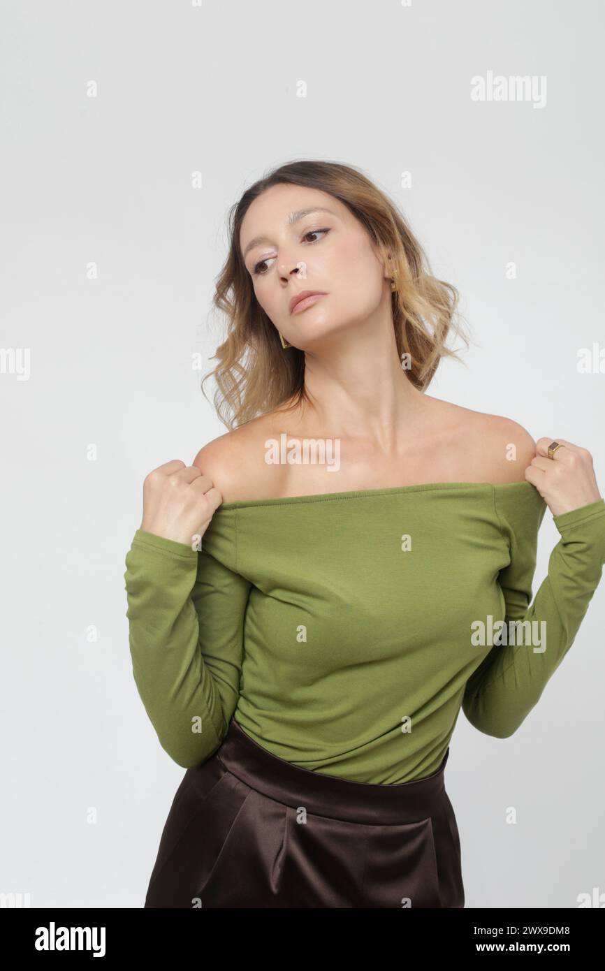 Serie di foto in studio di una giovane modella donna che indossa un comodo abito di base, camicia verde in viscosa e pantaloni marroni Foto Stock