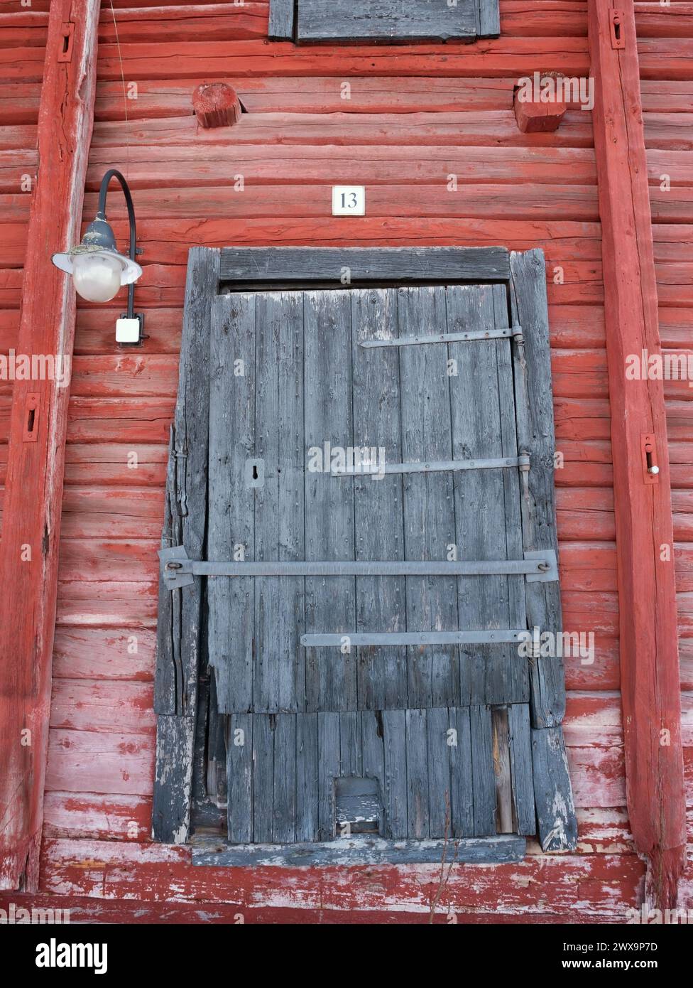 vecchia porta di deposito chiusa numero 13 dell'edificio in legno dipinto di rosso Foto Stock