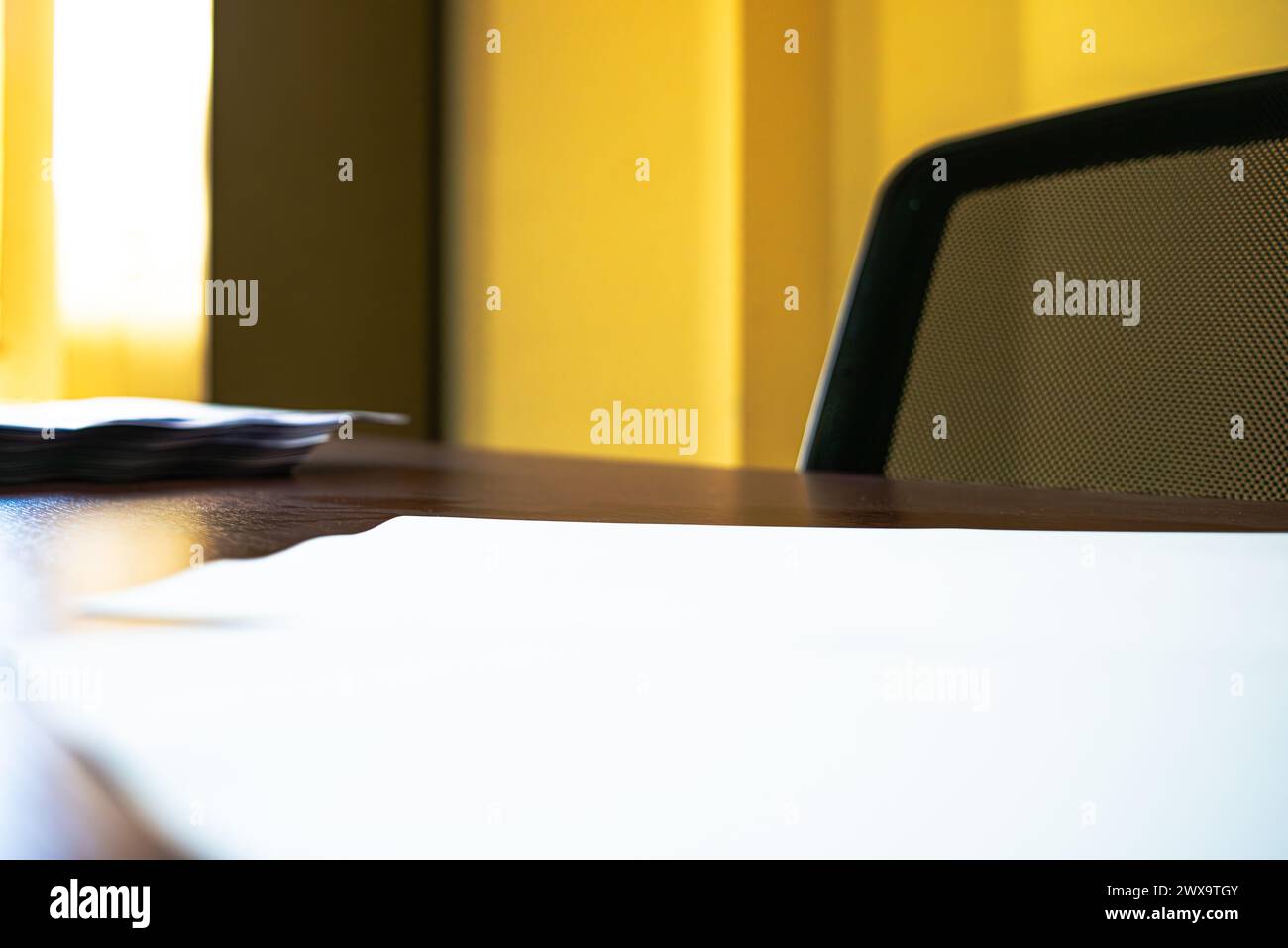 Una scrivania immacolata adornata con carta A4 bianca impilata, che crea uno spazio di lavoro organizzato ed efficiente per le attività professionali. Foto Stock