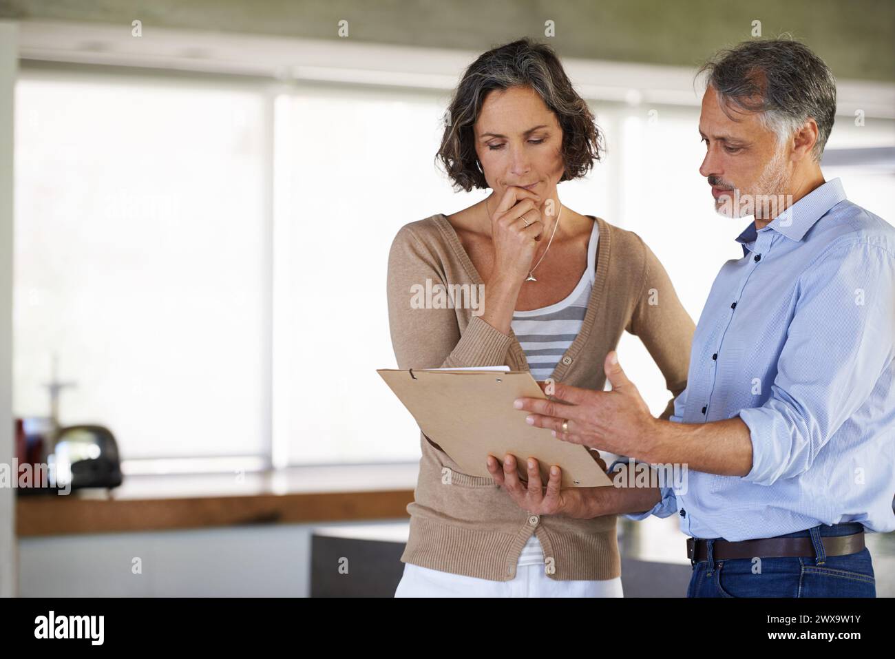 Serio, coppia e documenti in casa per bollette, budget o risoluzione di problemi per il debito. Lettera, uomo e donna maturi con le tasse, fallimento e lettura male Foto Stock