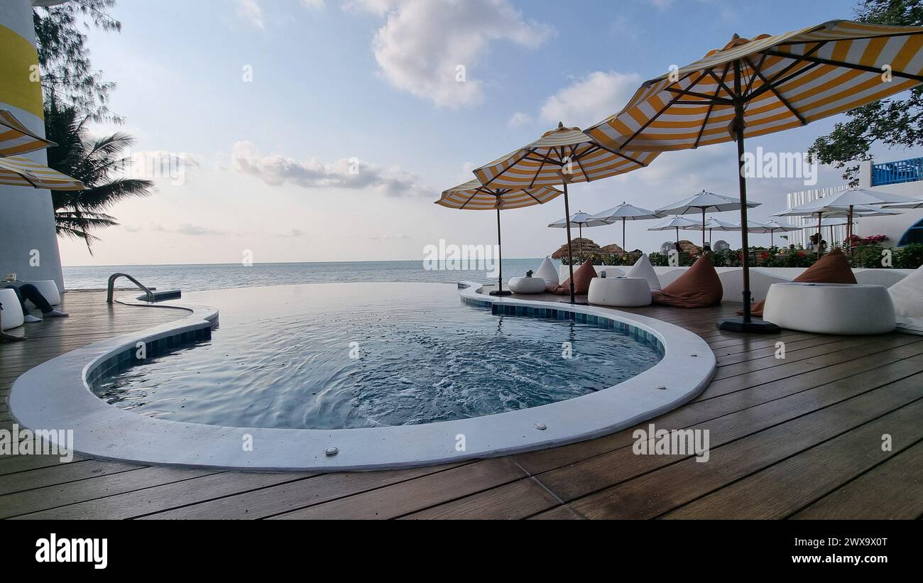 Bangsaray Pattaya Tailandia 28 febbraio 2024, Una scintillante e grande piscina circondata da ombrelloni colorati e sedie invitanti, a creare un ambiente tranquillo e rilassante sotto il sole. Foto Stock