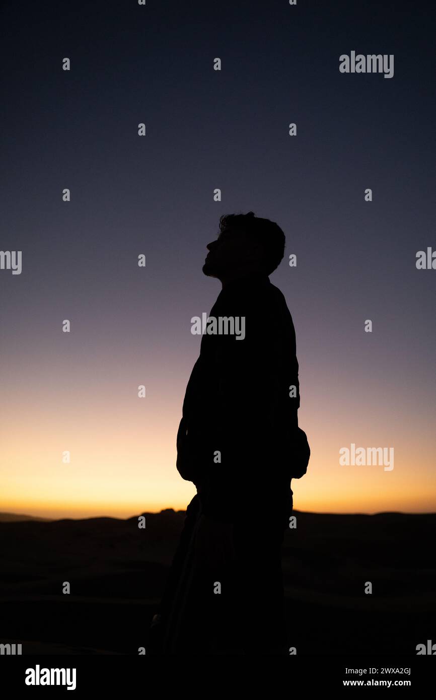 Una foto verticale di un uomo con silhouette sullo sfondo del tramonto Foto Stock