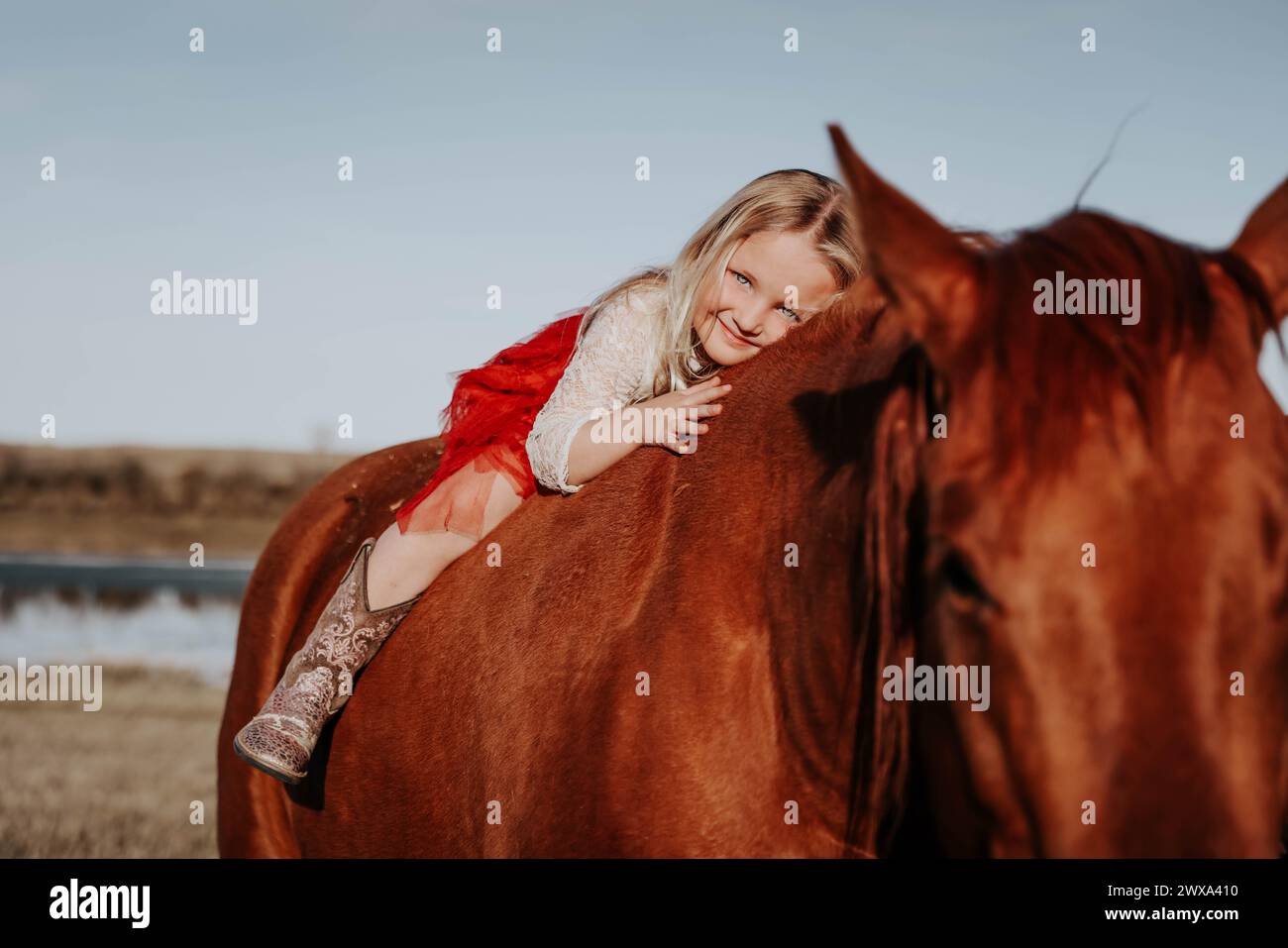 Fascino biondo: Bambina di 4 anni e il suo legame indistruttibile con la forgia del cavallo! Foto Stock