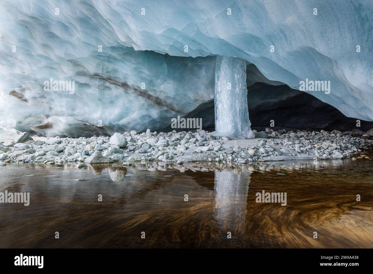 Una grotta ghiacciata con una cascata ghiacciata che si riflette nell'acqua di Zinal Wallis, Svizzera Foto Stock