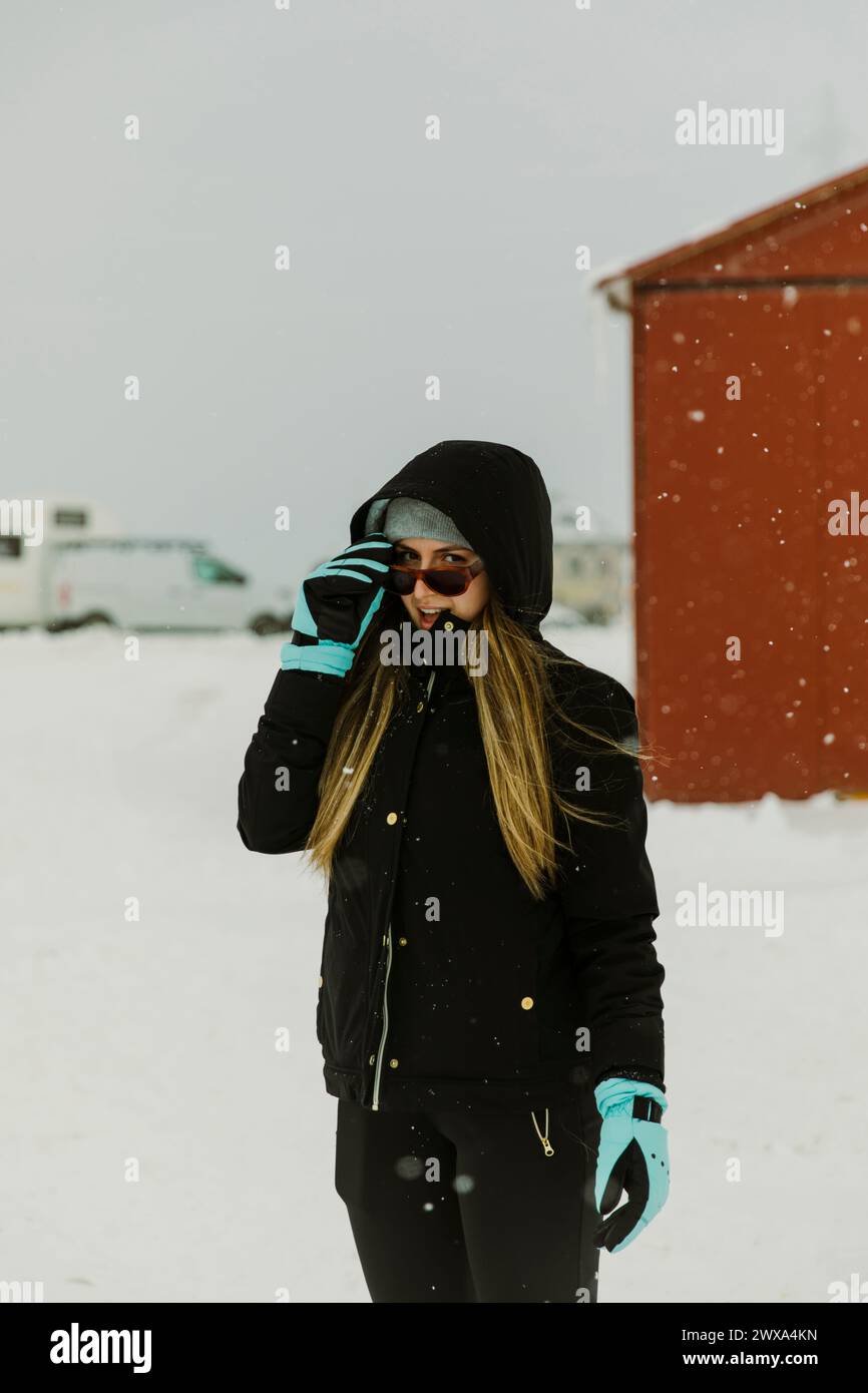 Ragazza in abiti invernali circondata dalla neve sorridente alla macchina fotografica Foto Stock