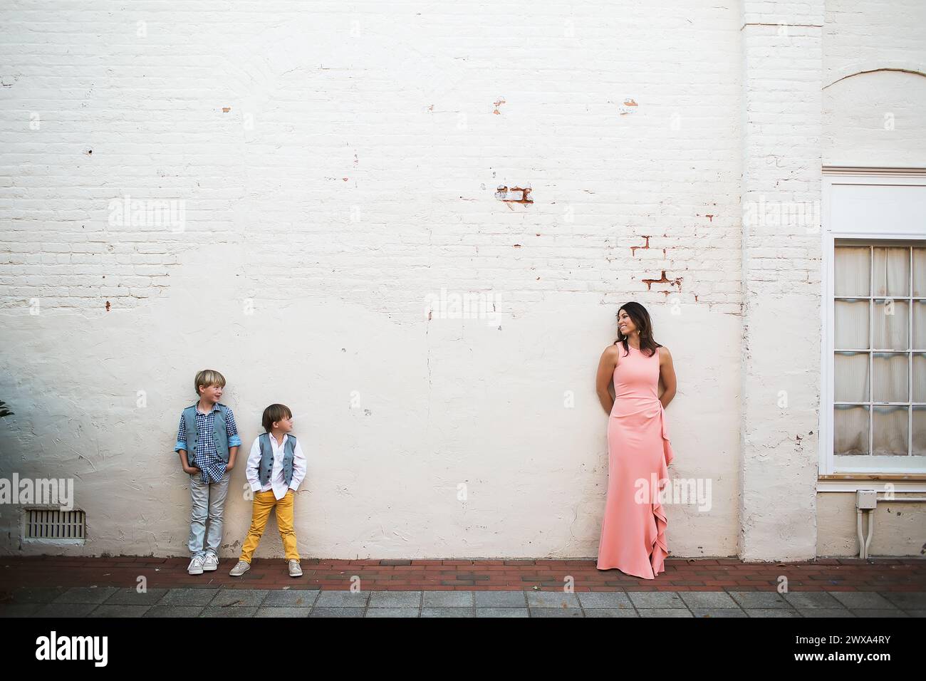 Una madre elegante sorride accanto ai figli vestiti in modo informale Foto Stock