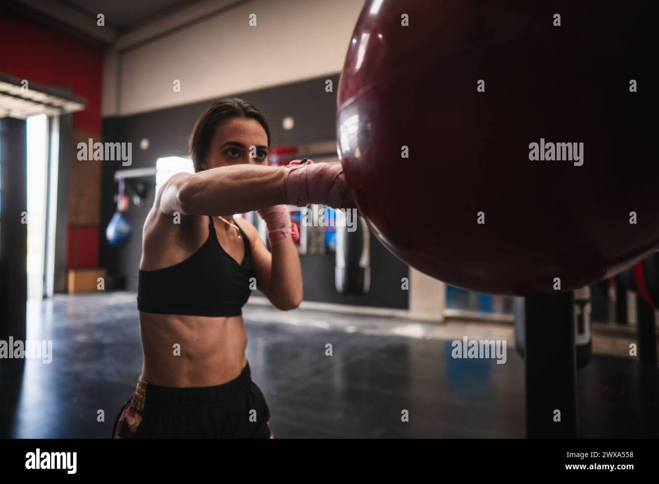 Adatta l'allenamento di pugile femminile su una borsa da pugno in palestra Foto Stock