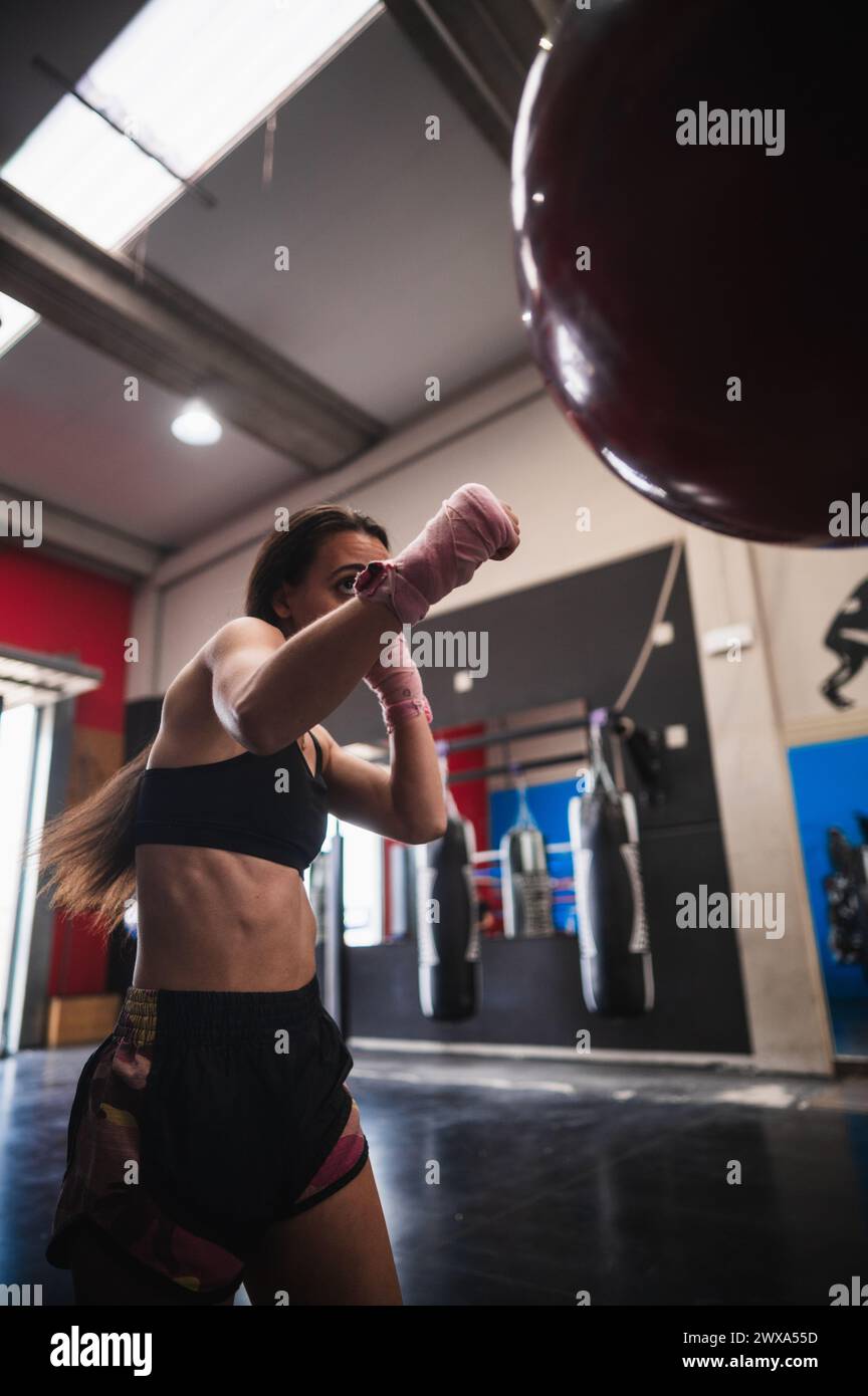 Fit sportivo che si allena con una borsa per punzonare in palestra Foto Stock