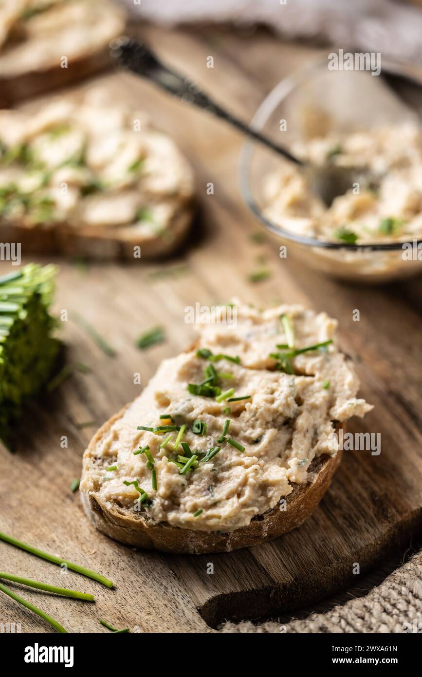 Primo piano di fette di pane con tradizionale bryndza slovacco a base di formaggio di pecora con erba cipollina tagliata di fresco posta su legno rustico. Foto Stock