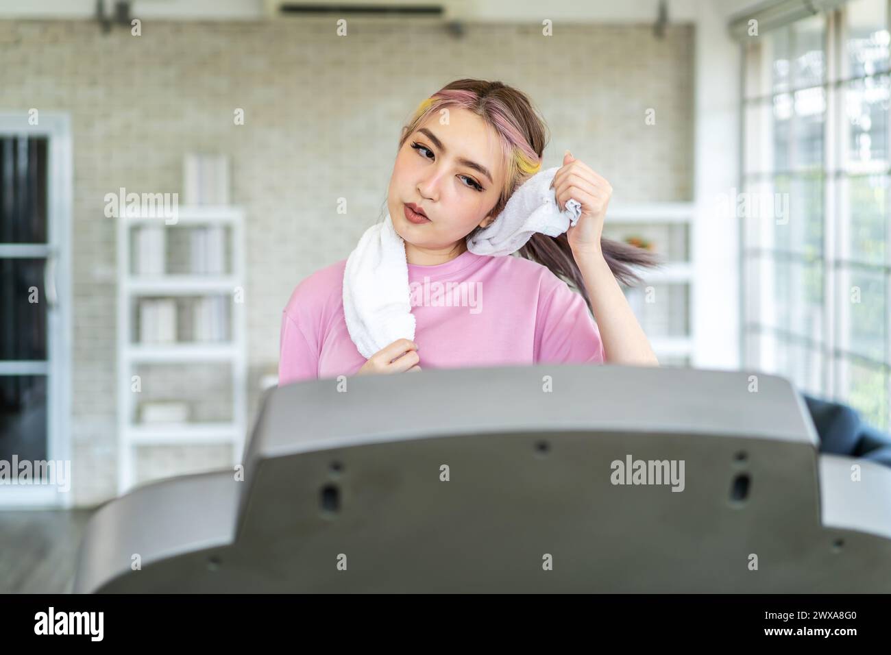 Una donna che asciuga il viso sul tapis roulant durante un allenamento Foto Stock