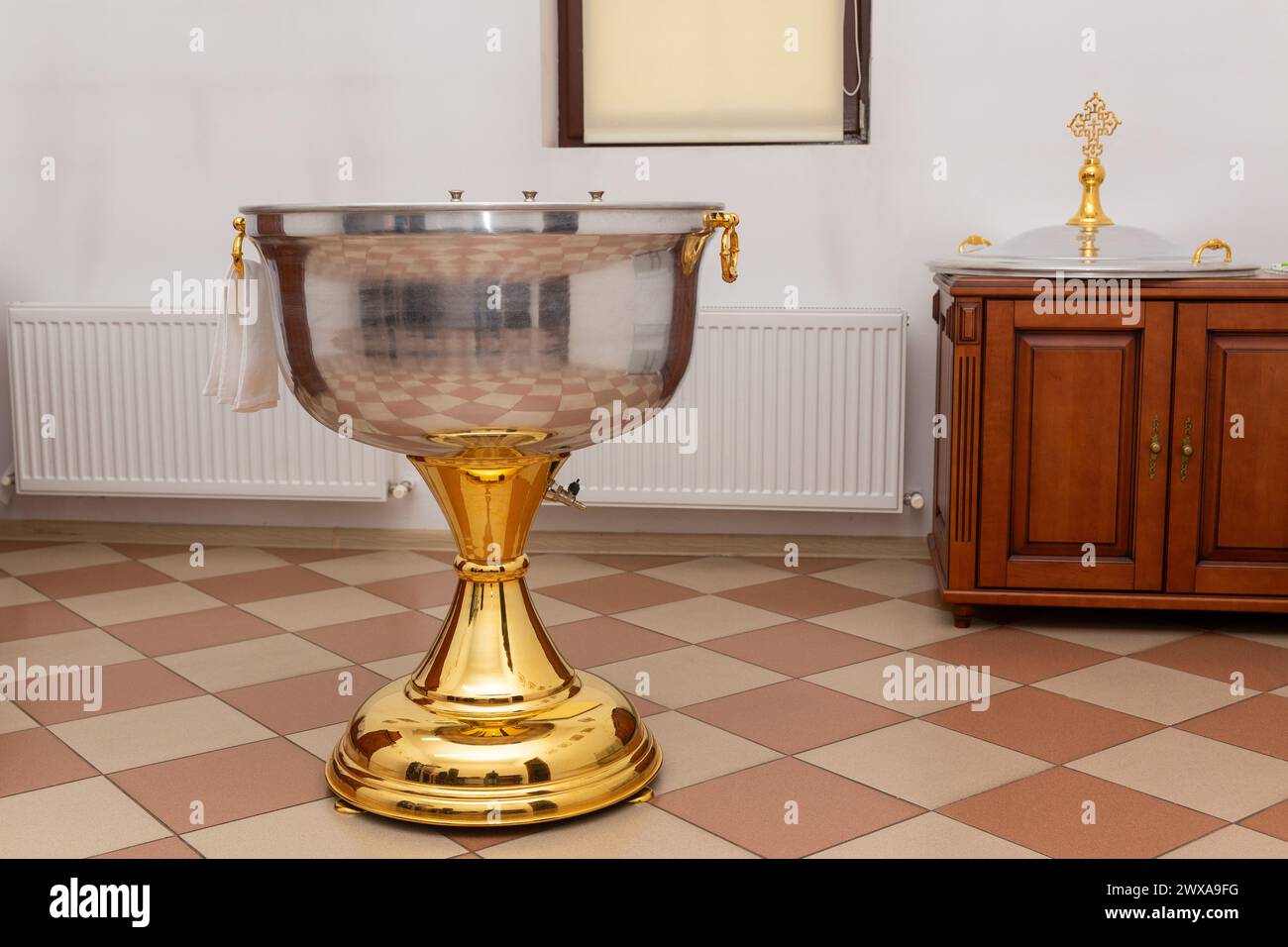 Fonte battesimale con acqua con asciugamano in una chiesa ortodossa. L'interno della stanza per il battesimo dei neonati nella Chiesa ortodossa. Foto Stock