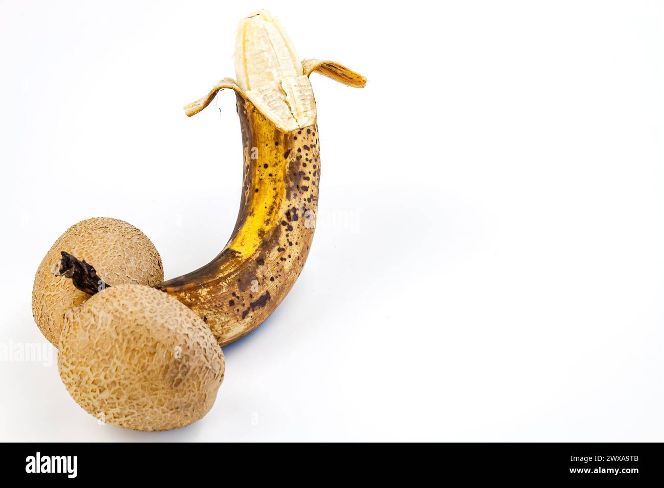Banana matura con macchie marroni su sfondo bianco. Foto Stock