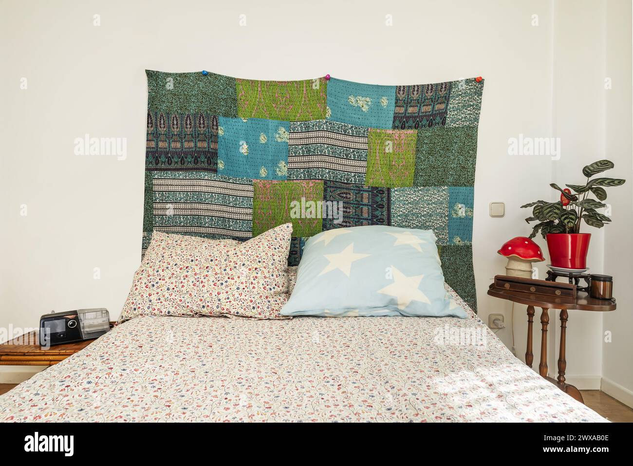 Testiera in tessuto della camera da letto con un grande letto con copriletto con stampe floreali Foto Stock