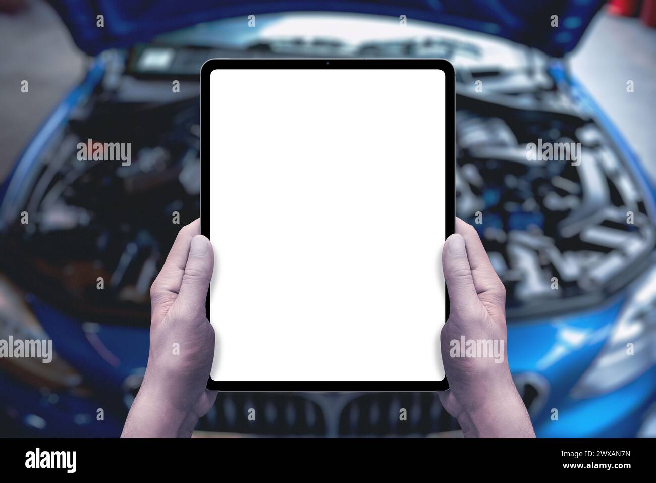 Il tecnico dell'assistenza tiene un tablet davanti a un'auto con vano motore aperto. Display isolato per promozione assistenza, applicazioni, vendita di ricambi Foto Stock