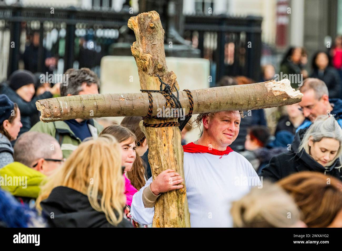 Londra, Regno Unito. 29 marzo 2024. Un uomo nella folla si veste da Gesù e porta una croce fatta in casa - la passione di Gesù da parte dei giocatori di Wintershall in Piazza Trafalgar il venerdì Santo. Un evento del fine settimana di Pasqua sostenuto dal sindaco di Londra, dove circa un centinaio di giocatori ritraggono gli ultimi giorni di Gesù, compresa una realistica interpretazione della crocifissione. Crediti: Guy Bell/Alamy Live News Foto Stock