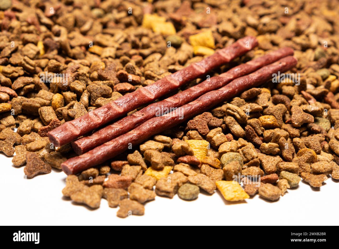 Dolcetti per gatti bastoncini di carne salsicce sullo sfondo di alimenti secchi. Dieta completa per gatti adulti. Foto Stock