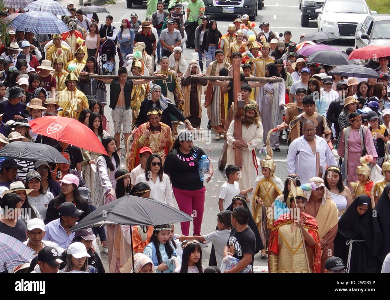 CUENCA-VIACRUSIS-SEMANA SANTA-TURI Cuenca, Ecuador 29 de marzo de 2024. Descalzo y con una cruz de madera de mas de 200 libras sobre sus hombros, Marco Pintado recorrio las 14 estaciones del via crucis de la parroquia Turi en Cuenca. El personifica a Jesus desde hace anos, cuando heredo el legado de su padre, que practico este rito por 14 anos, en la procesion en Honor de la Buena Muerte, una de las mas tradicionales que se Celebran en la capital azuaya en Semana Santa. La Procesion, que inicio a las 09:30 de hoy, viernes 29 de marzo de 2024, en los Tres Puentes, es liderada por un gru Foto Stock