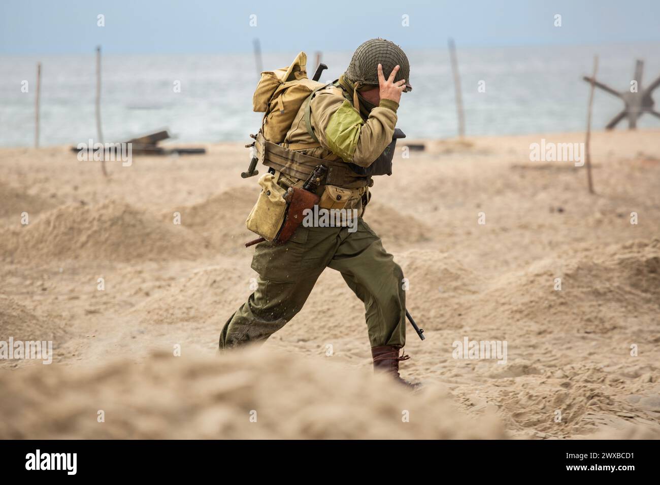 Ricostruzione storica. Un soldato di fanteria americano della seconda guerra mondiale che combatte sulla spiaggia. Foto Stock