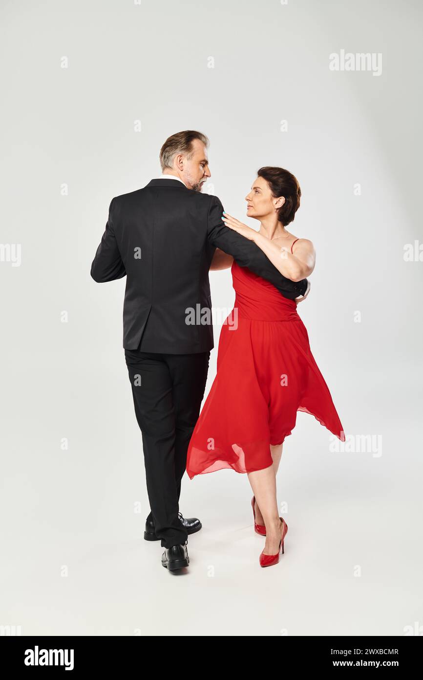 Foto a tutta lunghezza di una coppia matura e attraente in posa di danza tango isolata su sfondo grigio Foto Stock