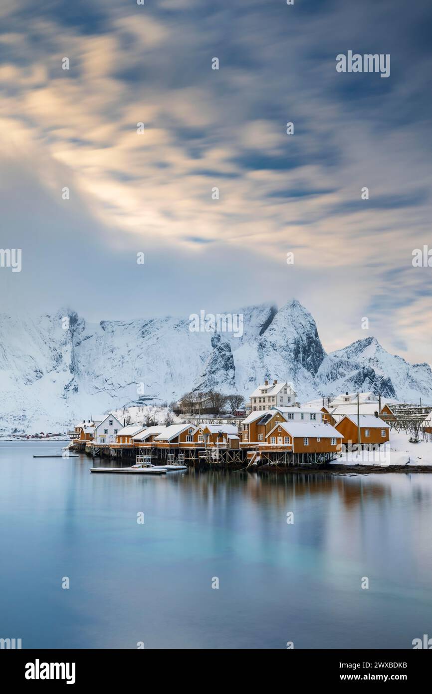 Tradizionali capanne gialle rorbuer sull'isola di Sakrisoy, montagne innevate sullo sfondo, Sakrisoy, Reine, Lofoten, Norvegia Foto Stock Tradizionali capanne gialle rorbuer sull'isola di Sakrisoy, montagne innevate sullo sfondo, Sakrisoy, Reine, Lofoten, Norvegia Foto Stock