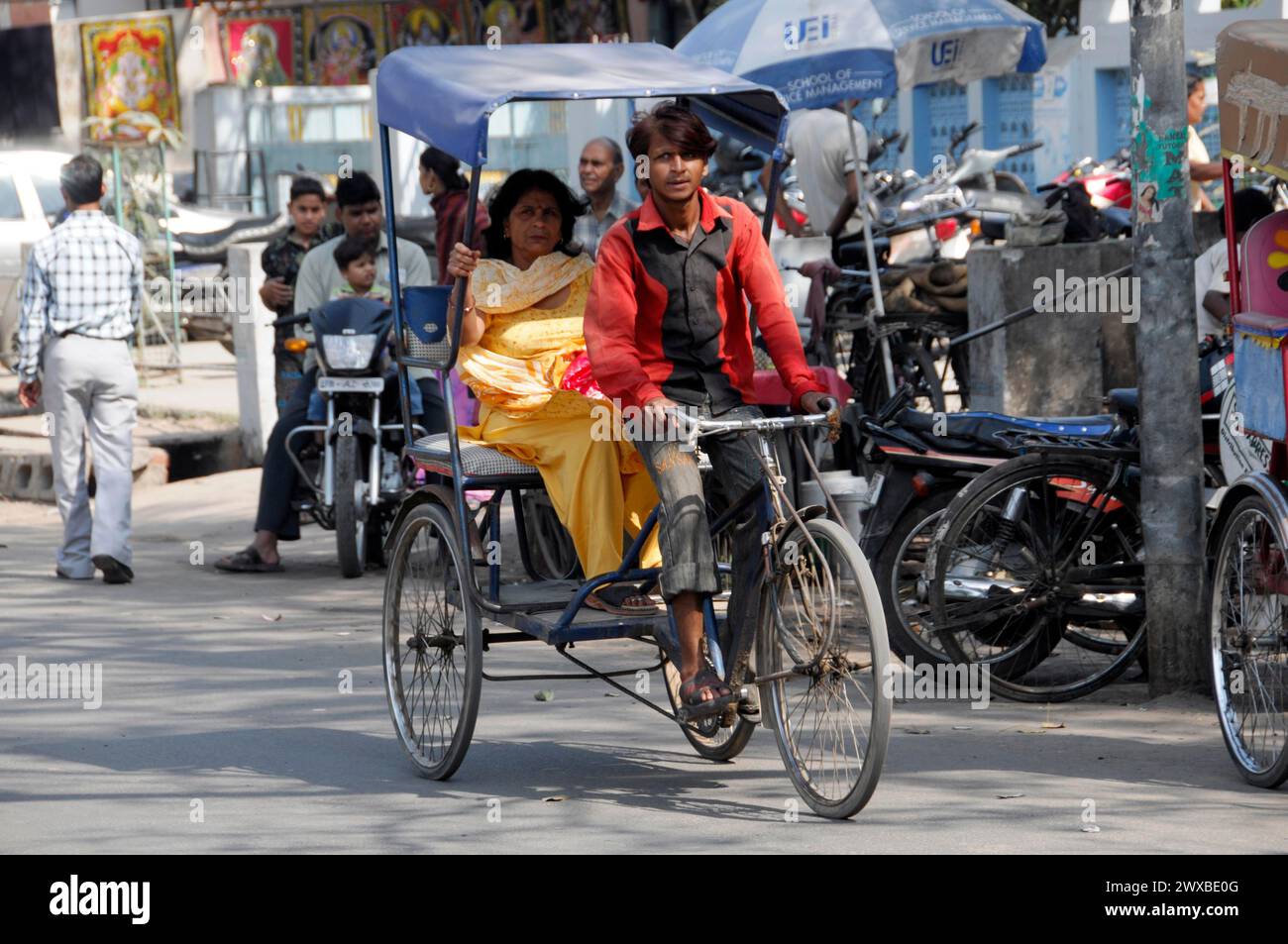 Un ciclista di risciò trasporta un passeggero in una strada cittadina, Jaipur, Rajasthan, India settentrionale, India Foto Stock