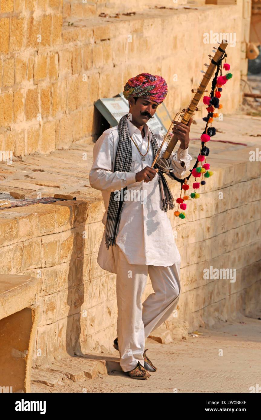 Musicista di strada in abiti colorati che suona uno strumento tradizionale a corde, Jodhpur, Rajasthan, India Foto Stock
