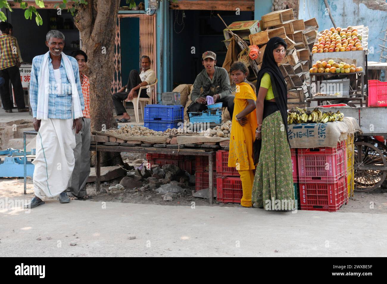 La gente del posto si trova in una bancarella di frutta e verdura in un vivace mercato di strada, il Rajasthan, India Foto Stock