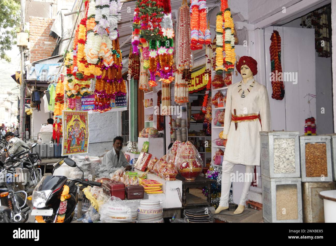 Un negozio di strada con statue religiose, prodotti tradizionali e un negoziante, Udaipur, Rajasthan, India settentrionale, India Foto Stock