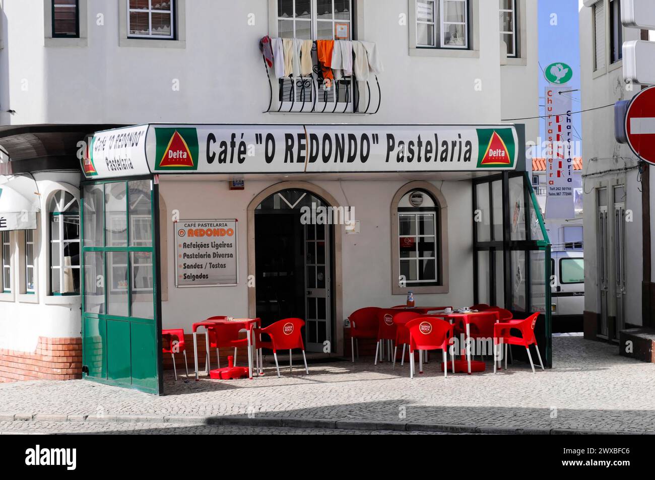 Nazare, Oeste, quartiere di Leiria, Street Cafe con sedie rosse e tavoli accanto a una pastelaria in un angolo affollato, Portogallo settentrionale Foto Stock