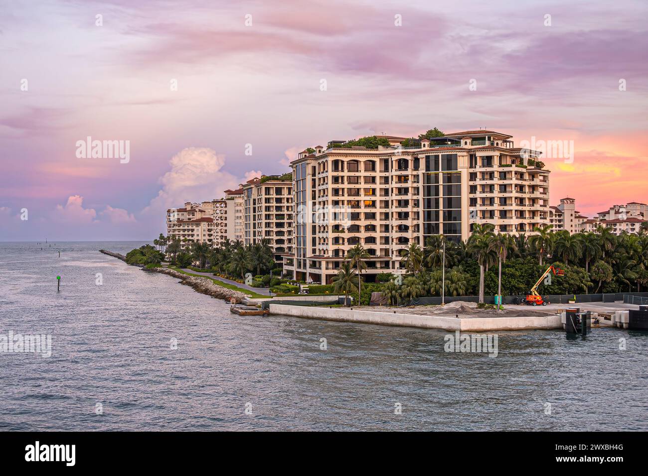 Miami, Florida, Stati Uniti - 29 luglio 2023: Condomini di lusso lungo la costa nord-orientale di Fisher Island e angolo sotto il cielo serale. Lavori di costruzione in corso. Mare Foto Stock