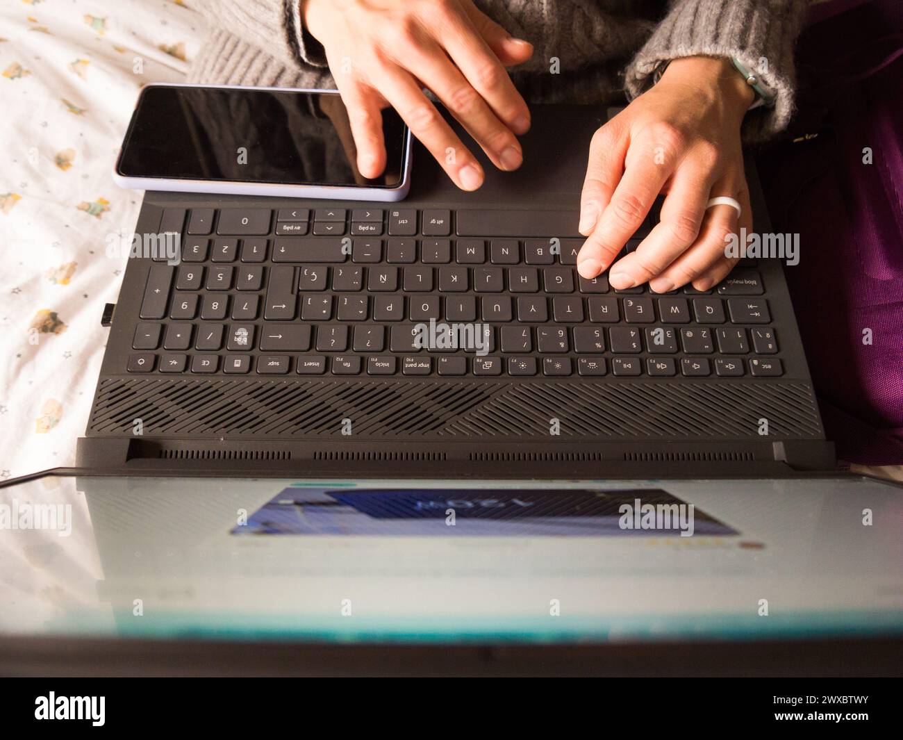 le mani di una donna sul computer portatile e sul telefono cellulare Foto Stock