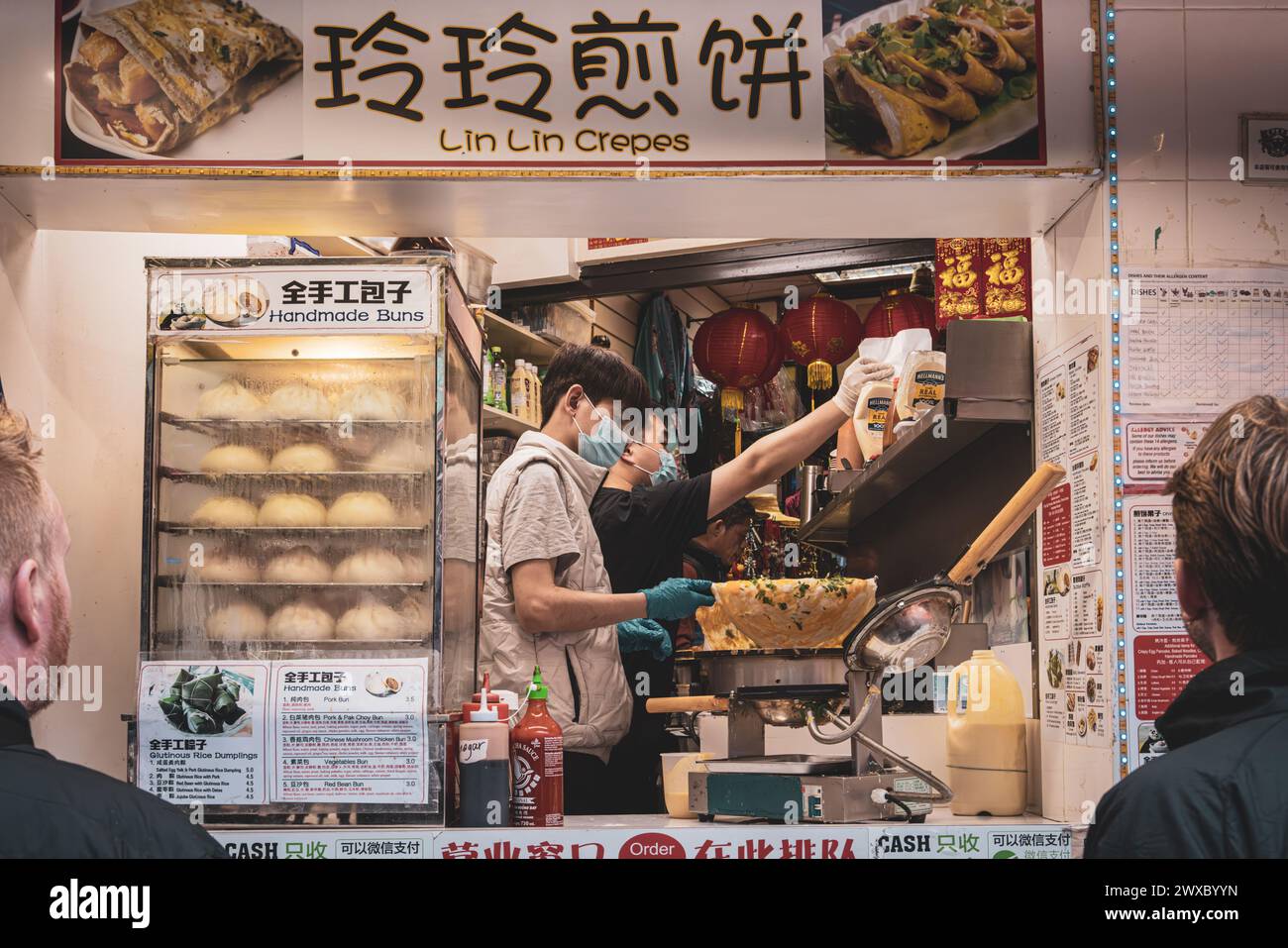 I clienti aspettano una deliziosa crepe cinese. Chiosco di cibo a Chinatown, Londra. Un gustoso pasto cinese preparato al momento. Cibo di strada appena cucinato. Foto Stock