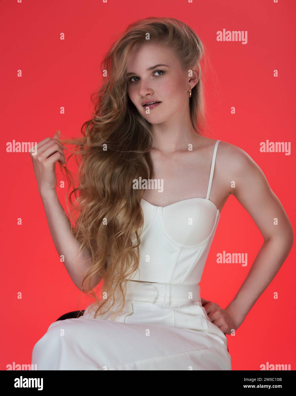 Ritratto di una giovane donna bionda vestita con un corsetto bianco scolpito. Headshot di una giovane modella della Gen Z con lunghi capelli biondi ondulati Foto Stock