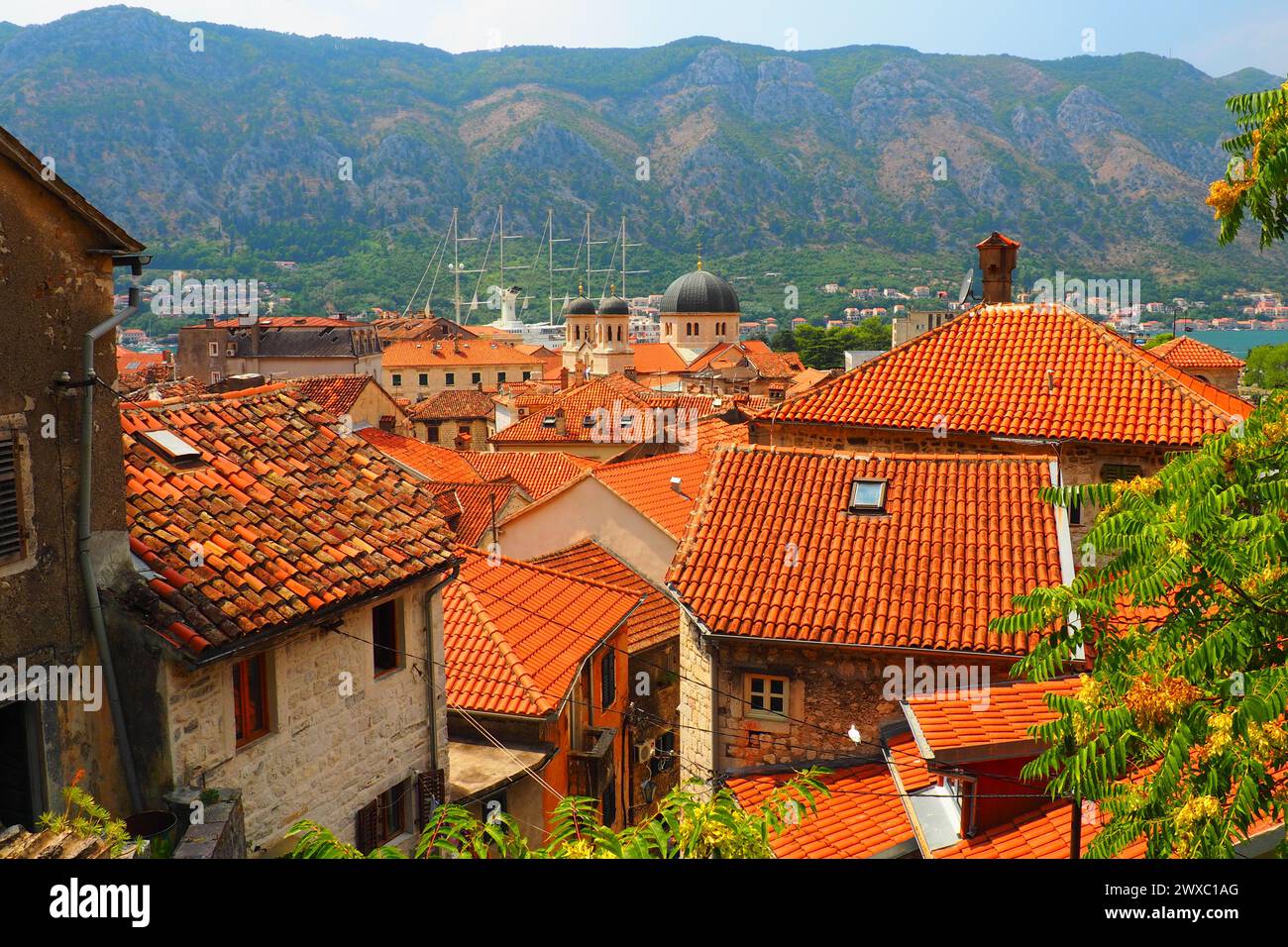 Kotor è una città costiera del Montenegro. Baia di Cattaro. Tetti di tegole rosse, montagne e camini di una nave turistica. Escursioni e turismo. Cattedrale di sa Foto Stock
