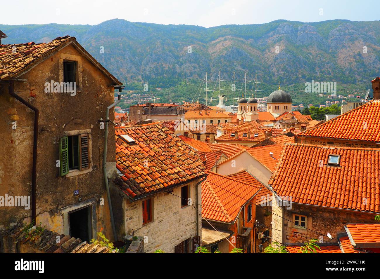 Kotor è una città costiera del Montenegro. Baia di Cattaro. Tetti di tegole rosse, montagne e camini di una nave turistica. Escursioni e turismo. Cattedrale di sa Foto Stock
